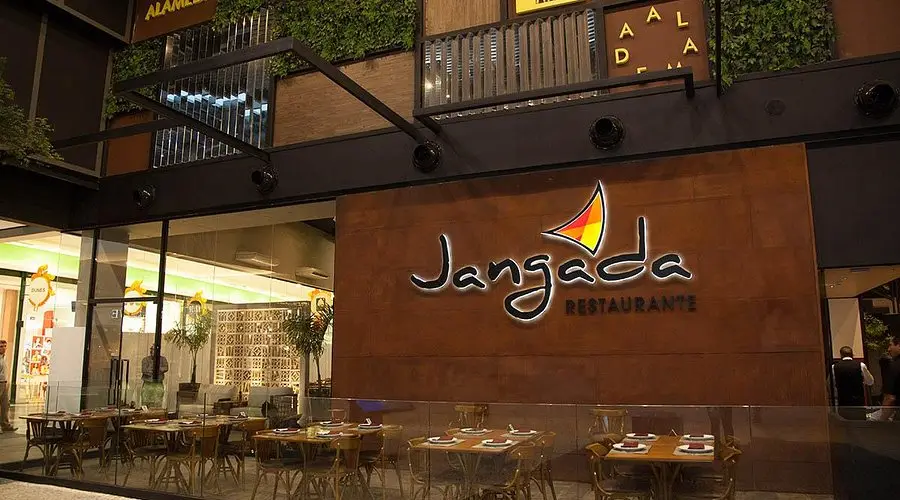 Jangada Restaurant exterior with modern decor, outdoor seating, and a prominent illuminated sign, creating an inviting atmosphere.