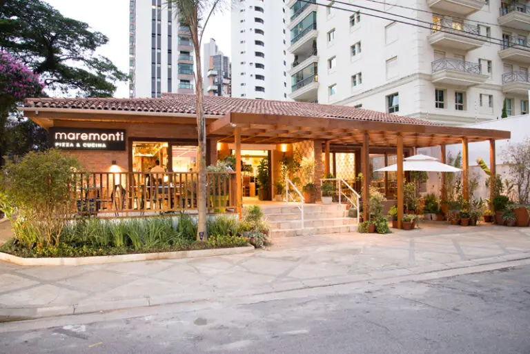 Maremonti restaurant with wooden patio, lush plants, and urban backdrop, offers a cozy dining experience in a bustling city setting.