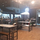 Industrial-style restaurant interior with black metal furniture, wooden floors, and globe light fixture.