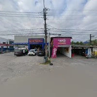 Wide-angle view of a street with two adjacent commercial storefronts (blue and pink signage), parked cars, overhead power lines, and cloudy sky.