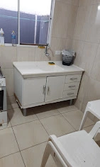 A compact, practical white kitchenette counter with under-sink cabinets, drawers, and tiled walls, located in a budget-friendly guest apartment.