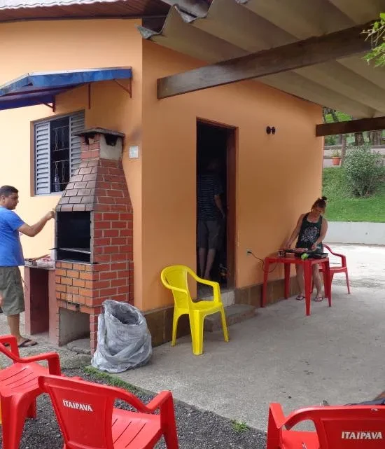 Outdoor Barbecue Gathering with Brick Grill and Red Chairs
