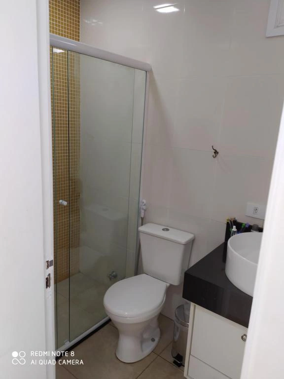 Modern small bathroom with glass walk-in shower, white toilet, and dark vanity counter with vessel sink.