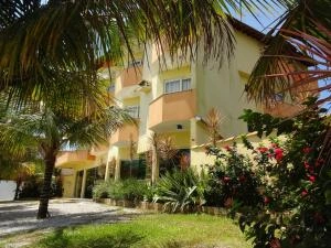 Palm trees framing the yellow exterior of a tropical hotel building with a paved stone entrance.