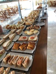Breakfast Buffet Sandwiches and Pastries High-angle view of a buffet counter displaying an assortment of fresh sandwiches, pastries, and baked goods on white platters, set in a bright dining room.