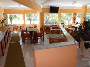 Spacious hotel dining room with orange walls, large windows, wooden tables, chairs, and a granite counter.