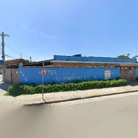 Bright blue front facade of a hotel with the name "SUÍTES", street number 440, and a WhatsApp contact number displayed in bold white lettering.