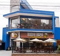 Modern two-story blue exterior of Buona Birra bar featuring an upper glass balcony and street-side seating.