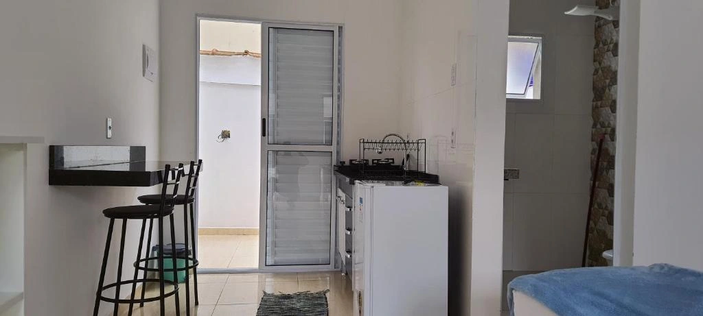 Functional kitchenette area with two black bar stools, white cabinets, stove, and a sliding glass door leading to an outdoor patio.