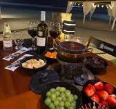 Evening table setting at Jolly Roger featuring a chocolate fondue, wine bottles, grapes, and fresh strawberries.