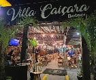 Open-air entrance to Villa Caicara Boteco, showcasing the wooden patio, hanging greenery, and bustling atmosphere.