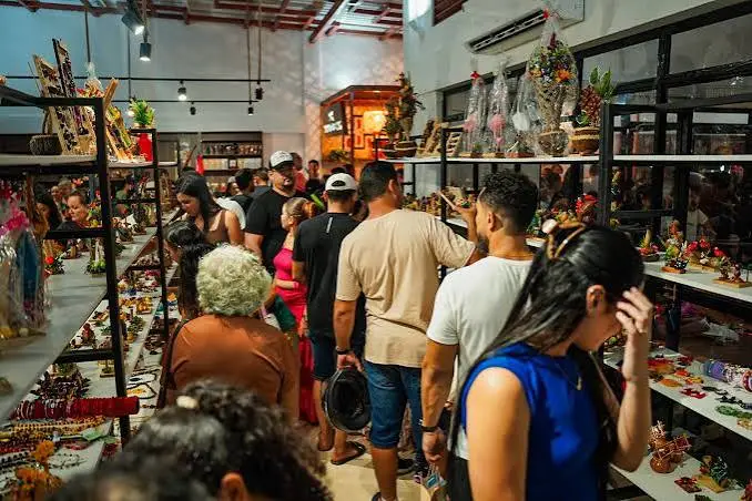 A busy, brightly lit retail space filled with shelves of souvenirs, miniatures, and local crafts, crowded with browsing customers.