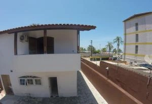 White two-story exterior of Pousada Costa Mare accommodation featuring a second-floor balcony, air conditioning unit, and traditional tiled roof.