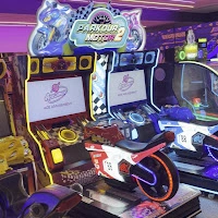 A close-up view of a "Parkour Moto 2" arcade racing game featuring a mounted motorcycle seat and vibrant neon graphics.