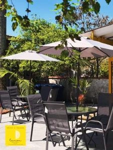 An outdoor courtyard with tables, chairs, and umbrellas surrounded by lush green trees on a sunny day.
