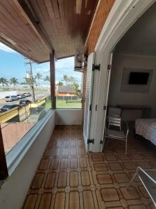 Scenic view from the wooden balcony of Pousada Costa Mare overlooking a street with palm trees and cars, connecting to a guest room.