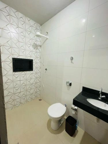 Modern bathroom with geometric tile wall, toilet, black vanity, and shower.