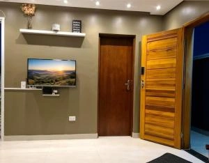 Modern living room with wall-mounted TV, shelves, and wooden doors.