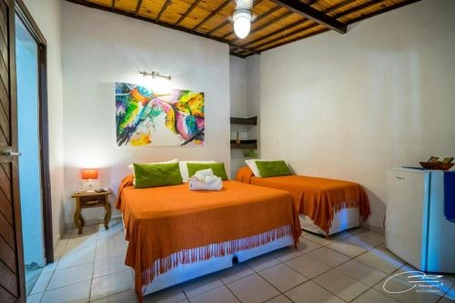Bright twin bedroom with orange bedding, green pillows, and colorful artwork.