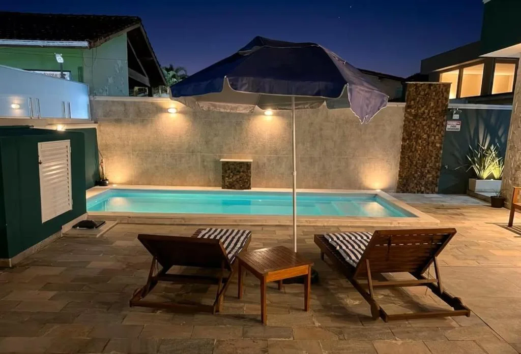 Illuminated pool at night with loungers, umbrella, and ambient lighting.