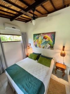 Cozy bedroom with teal bedding, green pillows, and parrot artwork.