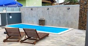 Backyard pool with wooden loungers, blue umbrella, and privacy wall.