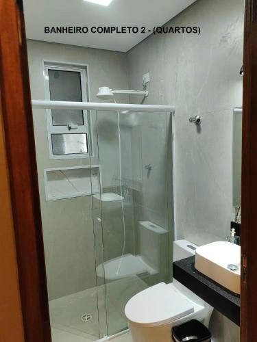 Modern bathroom with glass shower, white toilet, and vessel sink.