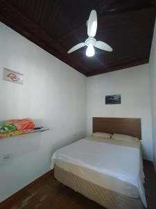 Cozy guest room featuring a double bed with white linens, wooden headboard, and ceiling fan.