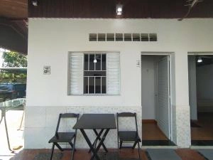 Covered outdoor patio area with a black table and chairs set against a white wall with a window.